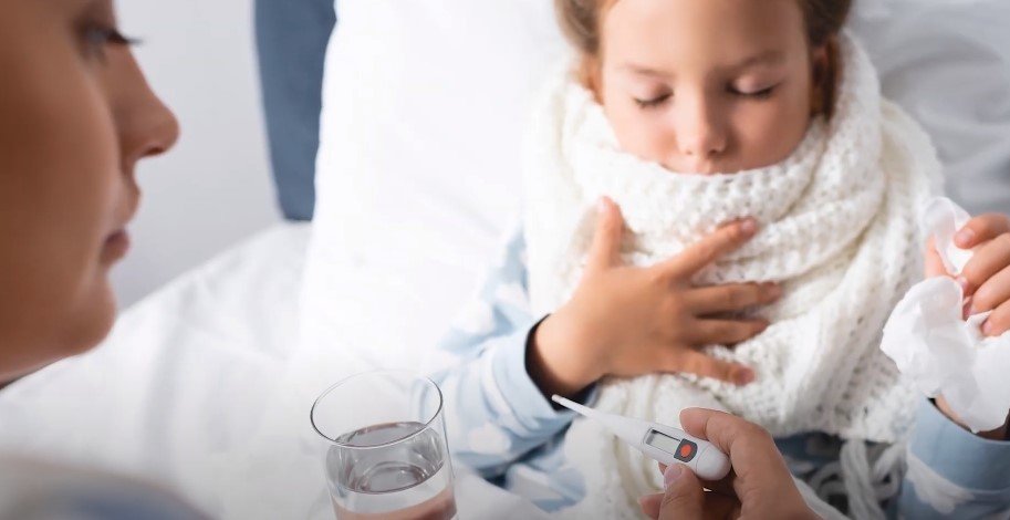 Mother Checking toddler fever of her child with digital thermometer.